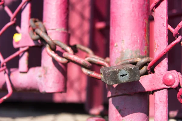 Antiguo candado y cadena en una valla rosa — Foto de Stock