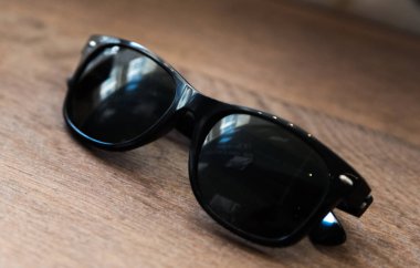 Ahşap bir masada siyah warfarrer güneş gözlüğü