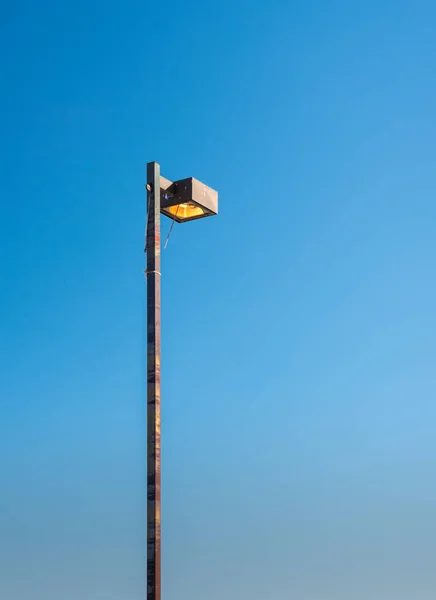 Grande pólo de luz de cidade metálica em um céu azul — Fotografia de Stock