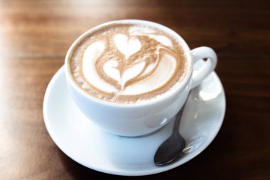 Ahşap masa üzerinde beyaz bir fincan kahve