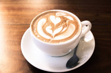 Ahşap masa üzerinde beyaz bir fincan kahve