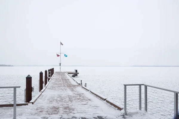 Cais com bandeiras em um lago congelado coberto de neve — Fotografia de Stock