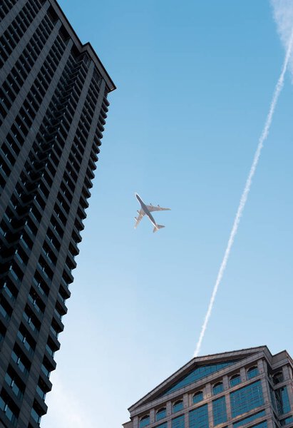 Big white airplane flies above Chicago buildings