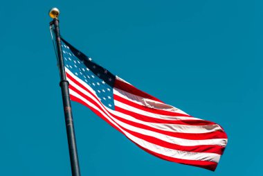 Açık mavi gökyüzünde dalgalanan Amerikan bayrağı