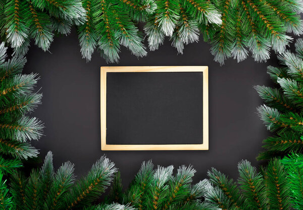 Christmas or New Year decoration on dark background: fir-tree branches, and drawing board. Banner mockup, postcard. Flat lay, top view
