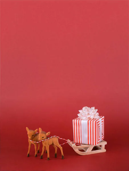 Christmas or New year background design. Reindeer with winter sleigh and gift box on red background. Christmas background with space for text. — Stock Photo, Image