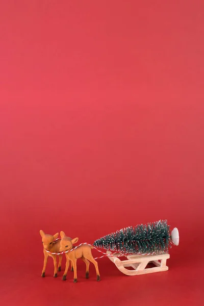 Boże Narodzenie lub Nowy Rok projektowania tła. Renifer z saniami zimowymi i choinką na czerwonym tle. Tło świąteczne z miejscem na tekst. — Zdjęcie stockowe