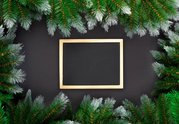 Christmas or New Year decoration on dark background: fir-tree branches, and drawing board. Banner mockup, postcard. Flat lay, top view