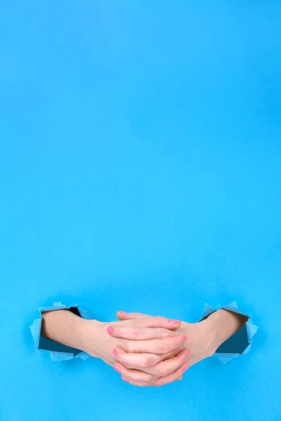 Girl hands close-up folded in a castle on a blue torn paper background. Hands symbolize the closeness, the experience. space for text on top. — Stock Photo, Image