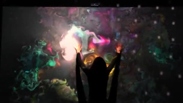 Girl plays with an interactive video installation. New art form, generative graphics. Silhouette of girl draws multi-colored paints interactive installation. — Stock Video