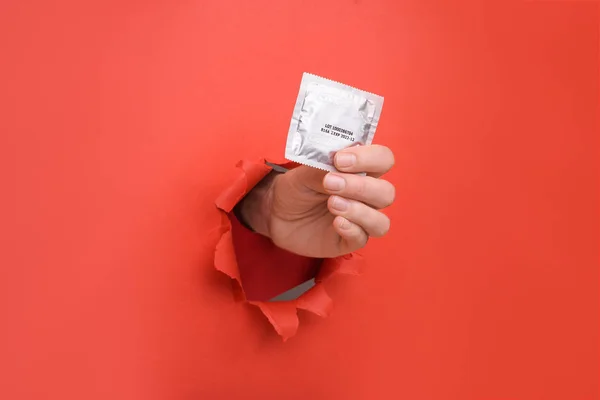 Kırmızı duvarda el prezervatifi var. Güvenli zevk ve koruma, doğum kontrolü, AIDS 'ten korunma ve AIDS' le savaşmak için gündüz. Reklam içeriğiniz için alanı bir kenara kopyalayın