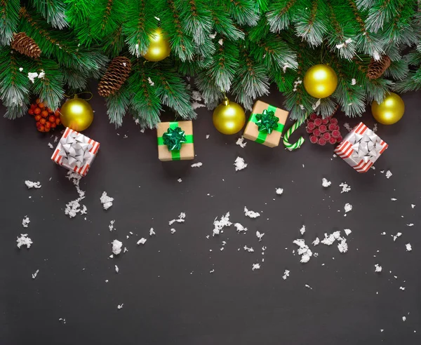 Buon Natale o felice anno nuovo composizione cornice. Rami di abete, giocattoli natalizi, confezione regalo, neve soffice, pigne, caramelle e bacche invernali su sfondo nero. Posa piatta, copiare lo spazio per il testo . — Foto Stock