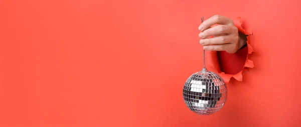 Ręczne trzymanie kuli lustrzanej Silver Disco na podartej czerwonej papierowej ścianie. Odłóżmy na bok miejsce na reklamę i ofertę lub treść sprzedaży. — Zdjęcie stockowe