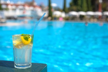 Rahatlatıcı bir tatil konsepti için dinlendirici Mojito kokteyli, dinlenme yeri havuzu ve şezlongları. Açık havuz arka planı