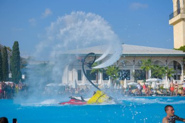 ANTALYA TURKEY 27 SEPT 2019: uçan giysili adam havuz otelinde havuz jeti veya su basıncı kuvvetiyle uçuyor. Güneşli havada kaydediliyor, genel plan.