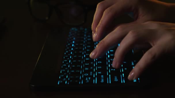 クローズアップ女性の手はオフィスのコンピュータの前に輝くLEDキーボード上のタイプのテキスト。女の子はLEDキーボードの後ろのオフィスでコンピュータで動作します。タブレットコンピュータで働く実業家. — ストック動画