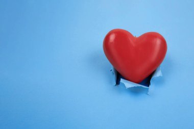 Kırmızı kalp, yırtık kırmızı kağıdın mavi arka planında. Kenarları pürüzlü ve yazı için yeri var. Sevgililer Günü tatili kavramı.