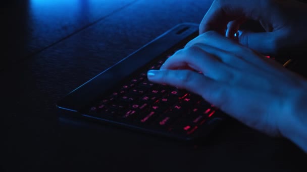 Ofisteki bilgisayarın önünde LED parlayan klavyede yakın plan kadın el yazısı. LED klavyenin arkasındaki bilgisayarda çalışan bir kız. Tablet bilgisayarda çalışan iş kadını. — Stok video