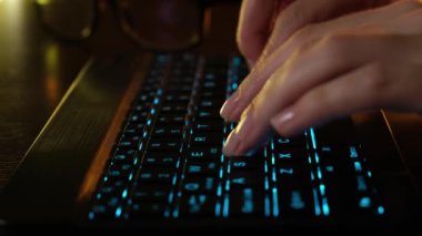 Ofisteki bilgisayarın önünde LED parlayan klavyede yakın plan kadın el yazısı. LED klavyenin arkasındaki bilgisayarda çalışan bir kız. Tablet bilgisayarda çalışan iş kadını.