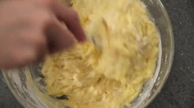 Kadın fırıncı cam tabakta kek hamuru yoğuruyor. Yakın çekim, yukarıdan görünüm.