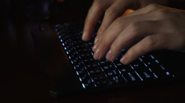 Ofisteki bilgisayarın önünde LED parlayan klavyede yakın plan kadın el yazısı. LED klavyenin arkasındaki bilgisayarda çalışan bir kız. Tablet bilgisayarda çalışan iş kadını.