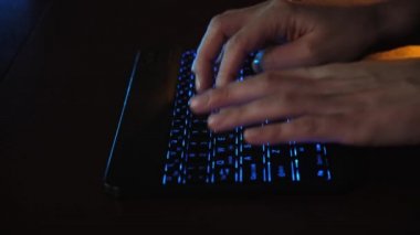 Ofisteki bilgisayarın önünde LED parlayan klavyede yakın plan kadın el yazısı. LED klavyenin arkasındaki bilgisayarda çalışan bir kız. Tablet bilgisayarda çalışan iş kadını.