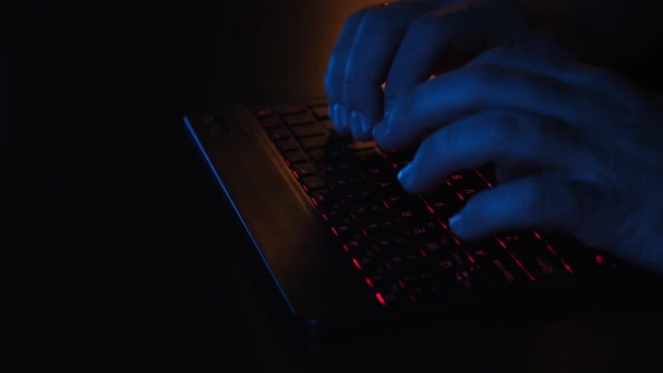 Klawiatura LED Close-up, man hands work at computer on LED keyboard in office at desk in rays of blue and red lighting. Koncepcja przedsiębiorstwa. — Wideo stockowe