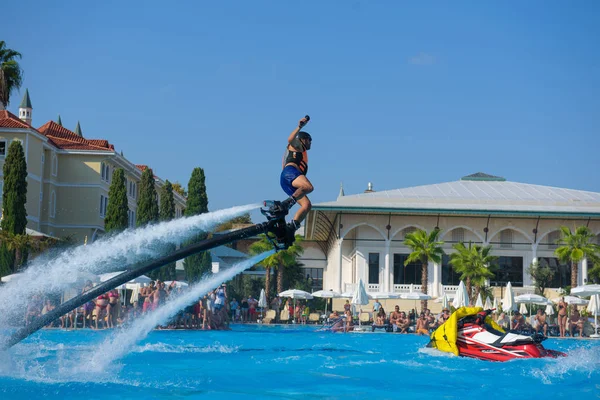 ANTALYA TURKEY 27 SEPT 2019: uçan giysili adam havuz otelinde havuz jeti veya su basıncı kuvvetiyle uçuyor. Güneşli havada kaydediliyor, genel plan.