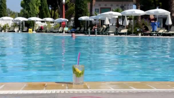 Coquetel Mojito fica no fundo da piscina durante o dia, no verão quente, a piscina é turva. — Vídeo de Stock