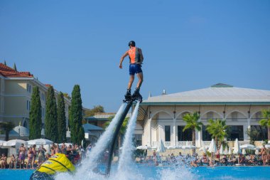 ANTALYA TURKEY 27 SEPT 2019: uçan giysili adam havuz otelinde havuz jeti veya su basıncı kuvvetiyle uçuyor. Güneşli havada kaydediliyor, genel plan.