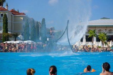 ANTALYA TURKEY 27 SEPT 2019: uçan giysili adam havuz otelinde havuz jeti veya su basıncı kuvvetiyle uçuyor. Güneşli havada kaydediliyor, genel plan.