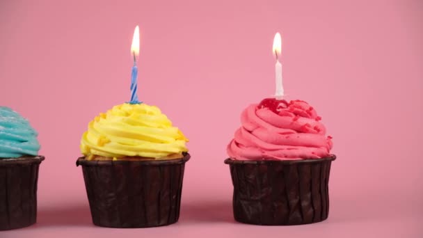Verjaardag cupcakes met aardbeien, citroen en bosbessen crème en brandende kaarsen op roze achtergrond. verplaatsen camera naar cupcake partij. — Stockvideo
