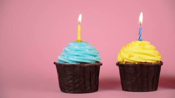 День рождения выдувает кексы с клубникой, лимоном и черничным кремом на розовом фоне. Перемещение камеры в кадре с кексами. день рождения концепции, загадать желание в день раздачи перед тортом — стоковое видео