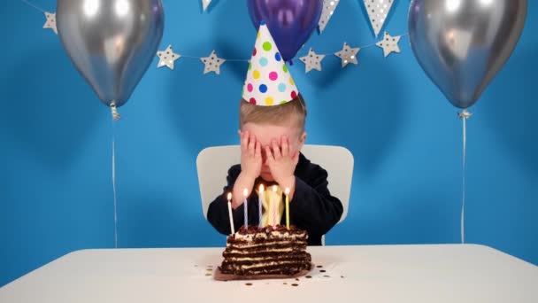 Cumpleaños chico sopló velas en la torta, niño pidió un deseo para su cumpleaños, fondo azul de globos festivos y decoraciones — Vídeos de Stock
