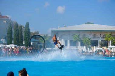 ANTALYA TURKEY 27 SEPT 2019: uçan giysili adam havuz otelinde havuz jeti veya su basıncı kuvvetiyle uçuyor. Güneşli havada kaydediliyor, genel plan.