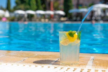 Rahatlatıcı bir tatil konsepti için dinlendirici Mojito kokteyli, dinlenme yeri havuzu ve şezlongları. Açık havuz arka planı