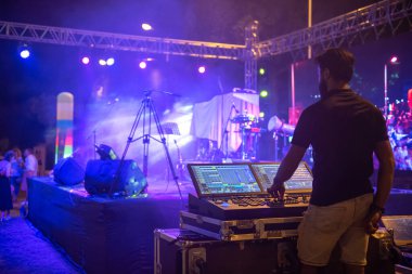 Ses mühendisi ekibi müzik konseri sahnesine hazırlanıyor. Ses mikserini ayarlıyorum. Sahnelerin önündeki bir konserde DJ 'lik yapacak.