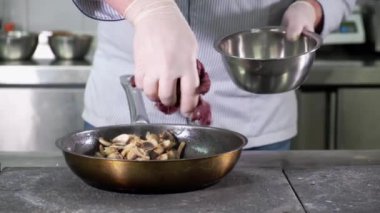 Mutfaktaki restoranda şef ellerini sıcak tavada geyik etine koyar. Mantar ve soğanlı.