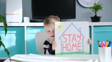 Coronavirus covid-19 sloganı evde kal. Evde kendini izole eden beyaz bir çocuk 