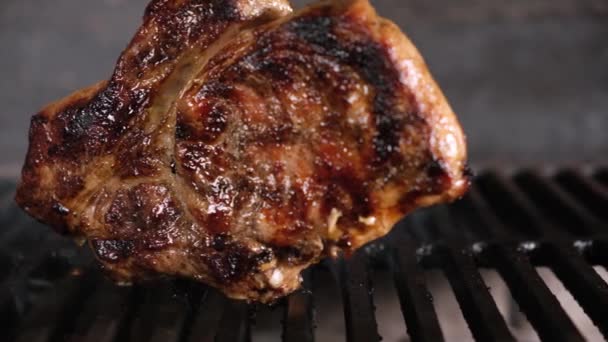 Grande bistecca dorata pronta con primo piano sulla griglia a carbone. Il fumo e il calore cuociono la carne di maiale sulla griglia. Dolly scorrevole video — Video Stock