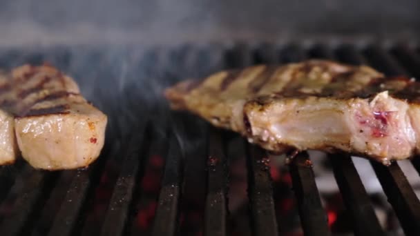 Two juicy steaks with golden crust and strips from grill are cooked on an open fire. Smoke and heat from grill to cook pork or beef. Dolly sliding video — Stock Video