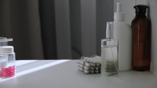 Vue de la paroi arrière de l'armoire de la trousse de premiers soins avec des médicaments, des vitamines, des antibiotiques, des bouteilles en plastique avec des antiseptiques et des désinfectants. Pilules rouges dans une bouteille transparente. Vidéo coulissante Dolly. — Video