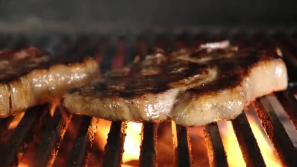 Слайд движения рамы два приготовления мяса барбекю на гриле. Жаркая свиная вырезка на открытом огне для барбекю. Закрыть сковородку огнем и дымом на жаровне. — стоковое видео