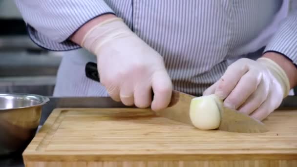 Chef παίρνει γάντζο αποφλοιωμένο κρεμμύδι από μεταλλικό μπολ και το κόβει σε λεπτές φέτες με μαχαίρι σε ξύλινο μπαμπού Διοικητικό Συμβούλιο στην κουζίνα εστιατόριο. Συρόμενο βίντεο Dolly — Αρχείο Βίντεο