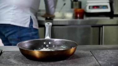 Restoran mutfağında aşçı tavada yemek hazırlar, soğan kızartır, mantar ve mantar atar ve her şeyi ayçiçeği yağıyla doldurup ahşap kaşıkla karıştırır. Dolly kaydırma videosu