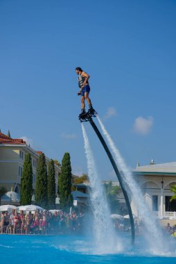 ANTALYA TURKEY 27 SEPT 2019: uçan giysili adam havuz otelinde havuz jeti veya su basıncı kuvvetiyle uçuyor. Güneşli havada kaydediliyor, genel plan