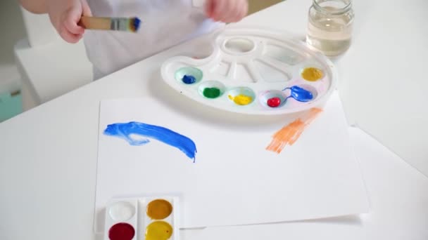 Ansicht oben Kind im Kinderzimmer Künstler zeichnet mit seinem Handpinsel mit blauer Farbe Himmel und blaue Wolken auf Papier Leinwand. — Stockvideo