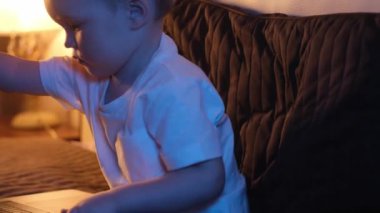 Beyaz çocuk gece geç saatlerde yatak odasında dizüstü bilgisayarını açıp internette ilginç bir şeyler yazıyor. Gece lambası odada, ay ışığı pencereden parlıyor. Dolly video üzerinden kayıyor.