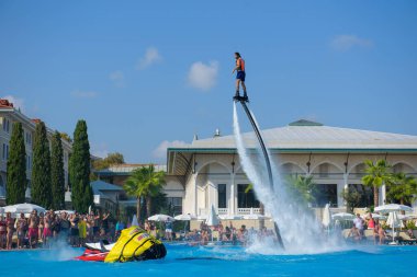 ANTALYA TURKEY 27 SEPT 2019: uçan giysili adam havuz otelinde havuz jeti veya su basıncı kuvvetiyle uçuyor. Güneşli havada kaydediliyor, genel plan.