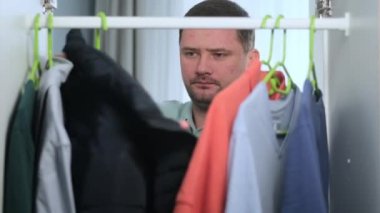 Tıraşsız Kafkasyalı sabahları gardırobu açar ve kıyafet seçer, gardırobu gözden geçirir, işe gitmek için mavi ceketi seçer. Adam randevuya göre giyiniyor, kamera kabine bakış açısı içinde.